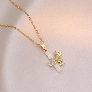 Vintage golden bunny and bamboo pendant necklace with sparkling zircon on silk background