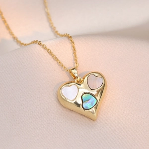 Golden heart necklace featuring inlaid shell pieces on smooth silk fabric background