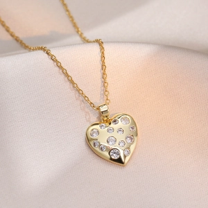 Collier élégant avec pendentif cœur doré serti de zircons sur fond de soie couleur champagne