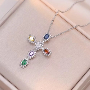 Collier pendentif croix en argent avec zircons colorés posé sur écrin en soie luxueux