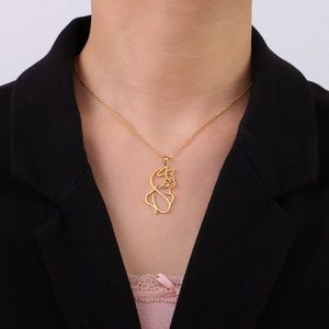 Elegante colgante de gato dorado en cadena fina usado por modelo sobre ropa oscura