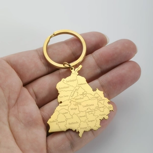 Detail of golden map-shaped keychain with Punjab laser engraving held in hand