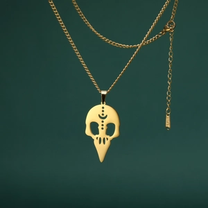 Detalle del colgante de calavera de pájaro en acero dorado con etiqueta S.STEEL