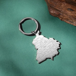 Detailed engraving of Punjab map on a silver stainless steel keychain over green surface
