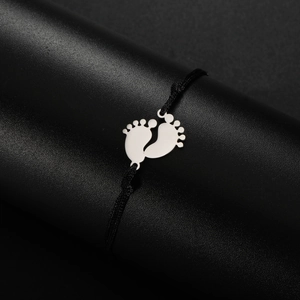 Detail of adjustable black woven bracelet with polished silver metal baby footprint pendants