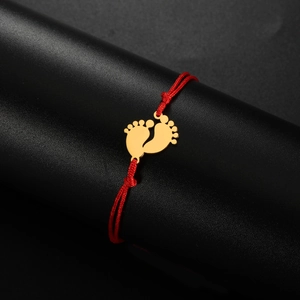 Detail of gold baby footprint pendant on a braided red cord adjustable bracelet