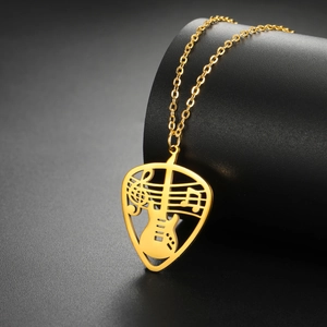 Detailed view of gold guitar pick pendant with hollowed musical notes and staff pattern