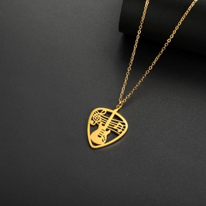 Macro detail of gold guitar pick necklace with music note cutout on black background