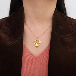 Detailed view of a gold guitar pick necklace with hollow musical notes on a model