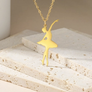 Close-up of golden ballet dancer pendant necklace on elegant stone background