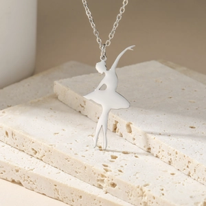 Detailed view of silver ballet dancer pendant on cross chain over travertine stone