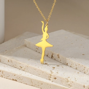 Close-up of golden ballet dancer silhouette pendant necklace on elegant stone background