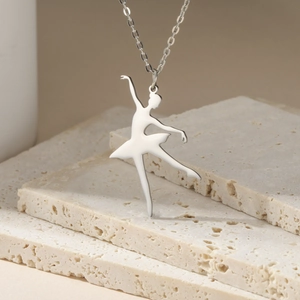 Close-up of a silver ballet dancer pendant with polished finish on beige stone slabs
