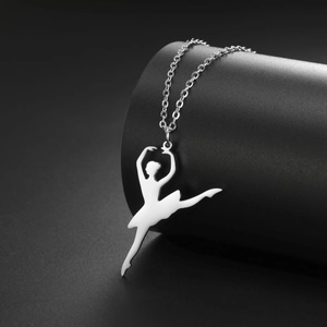 Macro shot of polished stainless steel ballet dancer pendant on a black cylinder