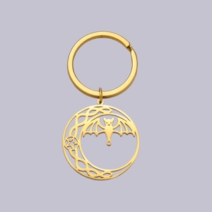 Macro detail of golden stainless steel keychain with hollow bat and celtic moon design