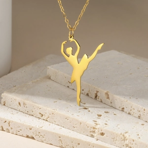 Macro shot of a polished golden ballet dancer pendant necklace on a natural stone surface
