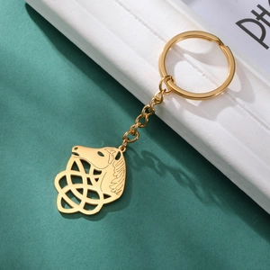Detailed close-up of golden Celtic knot horse head keychain on green textured background
