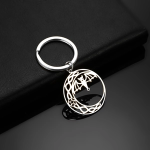 Detail of gothic stainless steel keychain with bat and celtic knot on black leather background