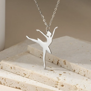 Detailed view of silver stainless steel ballet dancer pendant on a textured stone surface