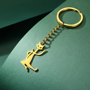 Detailed view of a golden kung fu cat keychain with polished finish on a textured background