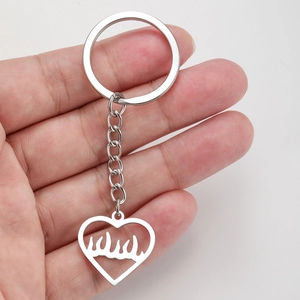 Porte-clés punk en acier inoxydable avec pendentif cœur enflammé tenu dans la main