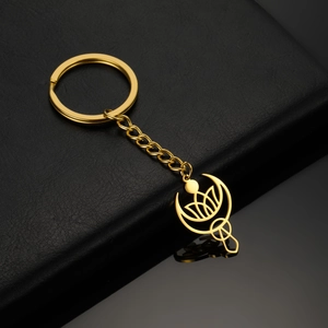 Vue macro du porte-clés doré lune et lotus sur cuir noir avec reflets élégants
