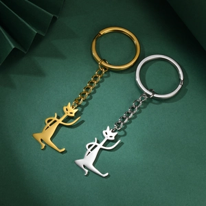 Polished gold and silver dancing cat keychains on decorative textured green paper