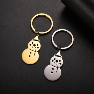 Close-up of gold and silver snowman keychains on textured black background