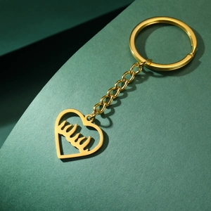 Détail d'un porte-clés doré en forme de cœur avec calligraphie arabe évidée
