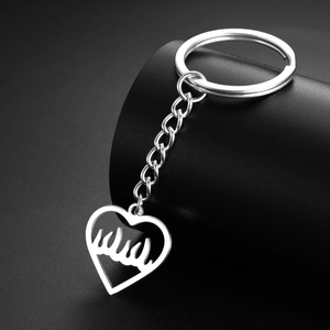 Détail du pendentif cœur en acier argenté avec découpe de flamme et chaîne sur fond noir