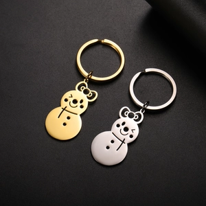 Detail of polished gold and silver snowman keychains with bow charms on black leather