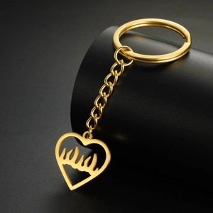 Détail d'un porte-clés cœur doré avec calligraphie ajourée sur un support noir mat
