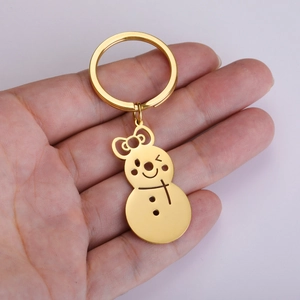 Golden snowman keychain with bow and wink face detail displayed in a palm for size scale