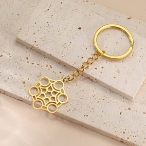 Gros plan du porte-clés doré en acier inoxydable avec pendentif hexagonal sur pierre