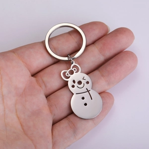 Close-up of cute silver snowman keychain with hollow bow held in hand for scale