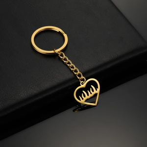 Détail d'un porte-clés en acier inoxydable doré avec calligraphie arabe sur cuir noir