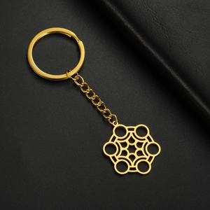 Détail macro du pendentif hexagonal en acier doré poli avec son anneau de clé