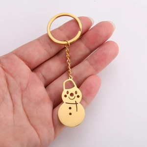 Macro detail of a golden snowman keychain with hollow-out design and polished mirror finish