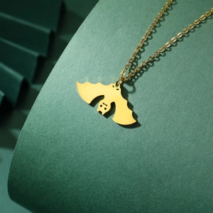 Dettaglio di una collana con pendente a pipistrello dorato su sfondo verde scuro