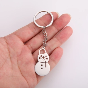 Detail of cute snowman stainless steel keychain pendant held in hand for scale