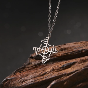 Macro shot of silver windmill pendant on dark wood featuring runic geometric symbols