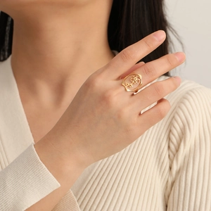 Bague fleur évidée en acier inoxydable plaqué or 18 carats portée sur l'index