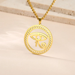 Macro shot of gold Eye of Horus pendant on a minimalist stone surface with detailed chain