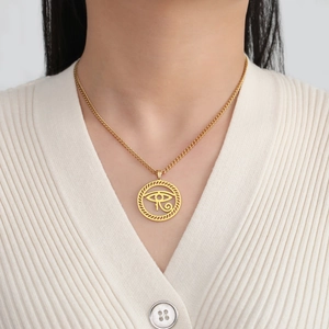 Close-up of golden Eye of Horus pendant necklace worn on a white ribbed top