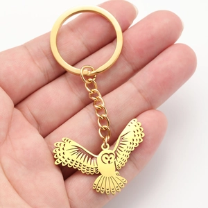 Détail du porte-clés pendentif chouette dorée ajourée tenu à la main pour la taille