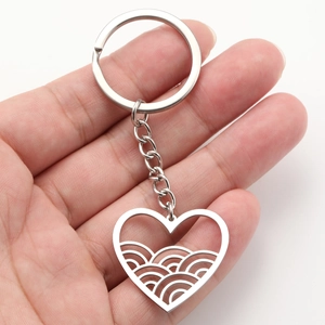 Polished stainless steel heart keychain with hollow wave pattern held in hand