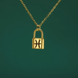 Detalle del colgante de candado dorado con signo de Piscis y cadena de acero pulido
