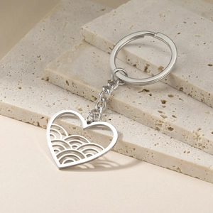 Minimalist stainless steel hollow heart and wave keychain on travertine stone surface
