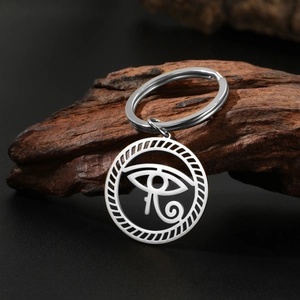Polished stainless steel Eye of Horus keychain hanging on rustic wood with black background