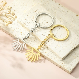 Close-up of gold and silver sunburst keychain pendants on a textured travertine stone